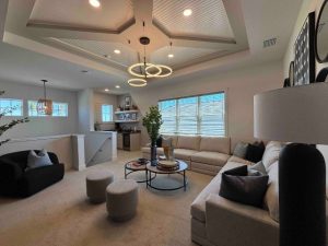 inside a custom lounge room. Stairs lead up to the room, comfortable seating lines the walls. A ceiling tray with decorative lighting sets the tone.