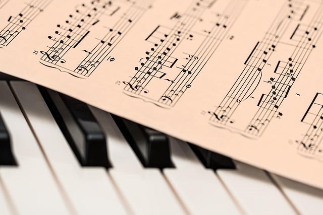 close up of piano keys with a sheet of pink music notation sitting cross them