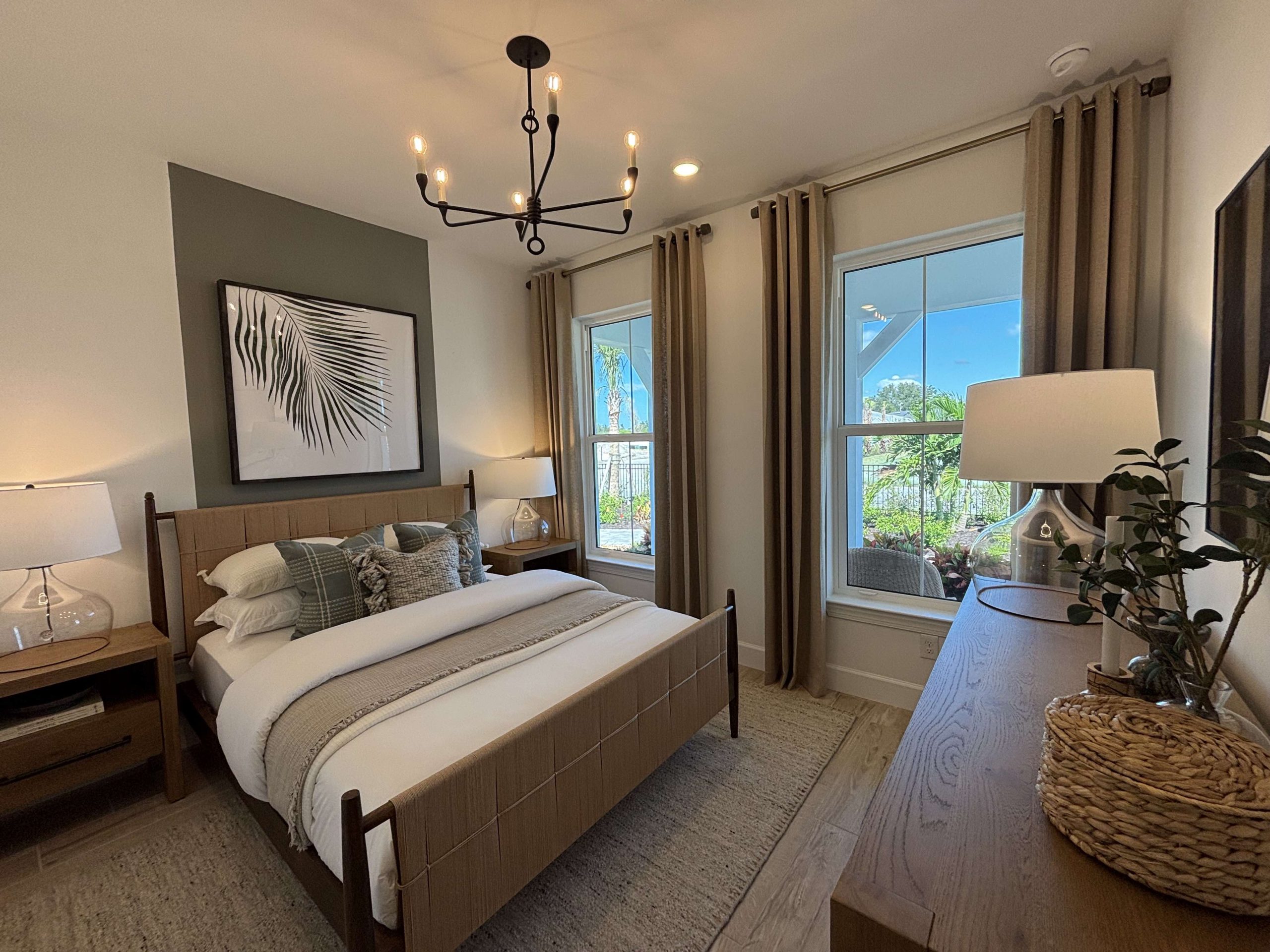 bedroom suite in shores decorated in earthy mocca latte tones. Big bay windows let lots of natural light into the room and a chandelier style light hangs above a freshly made kingsize bed. The room gives high-spec but homely vibes.