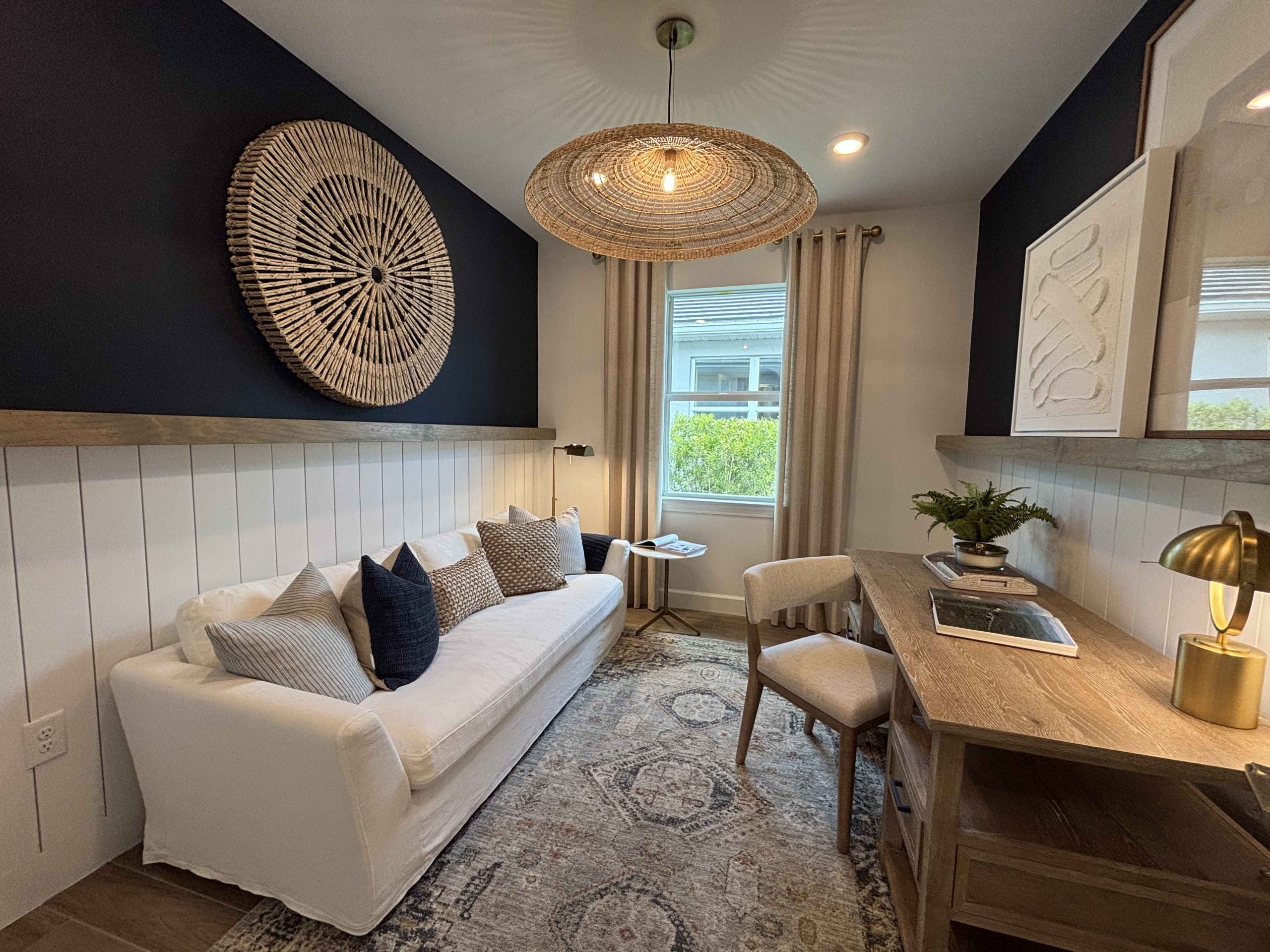 flex room with sofa, desk, and wall hanging creating a cozy nook