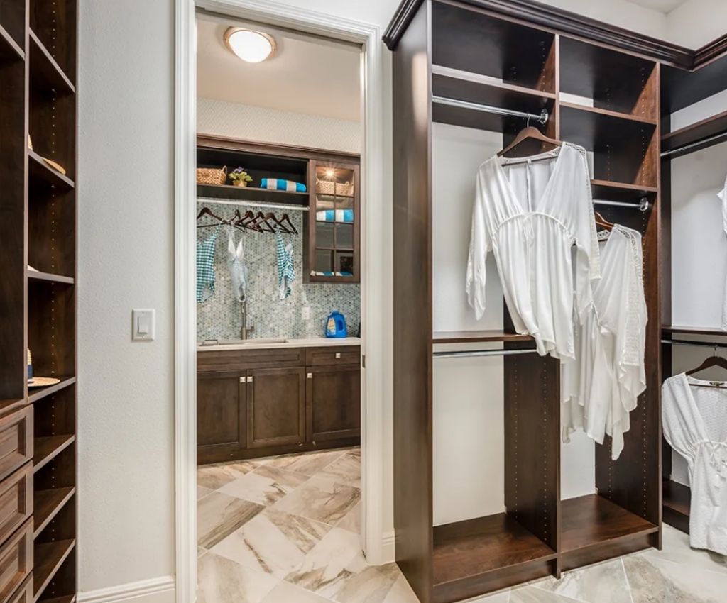 custom designed walk in closet space with lots of different sized areas for different storage needs. A doorway leads through to a matching bathroom suite.