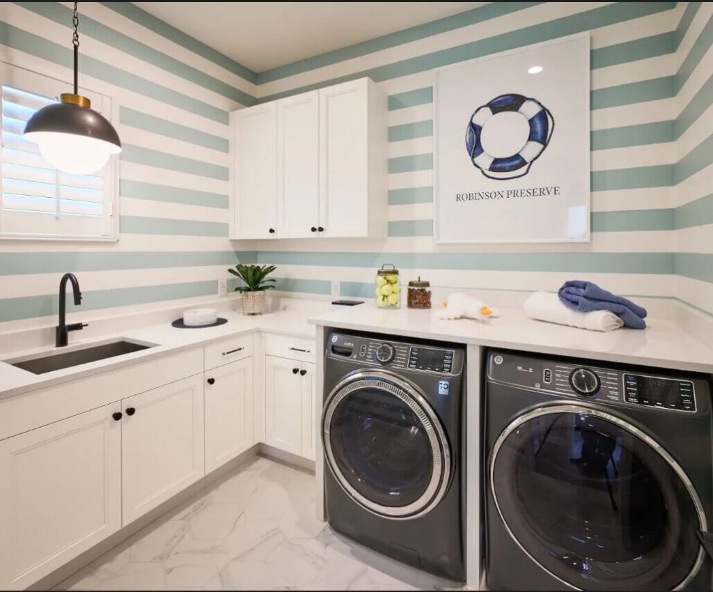 practical utility room with under counter washer and dryer, counter top sink, and wall cupboard.
