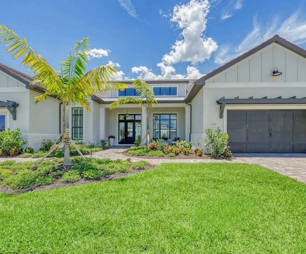 exterioro of the neal signature homes palm bay 2 model, with double garage doors, set back door, and lush green lawn.