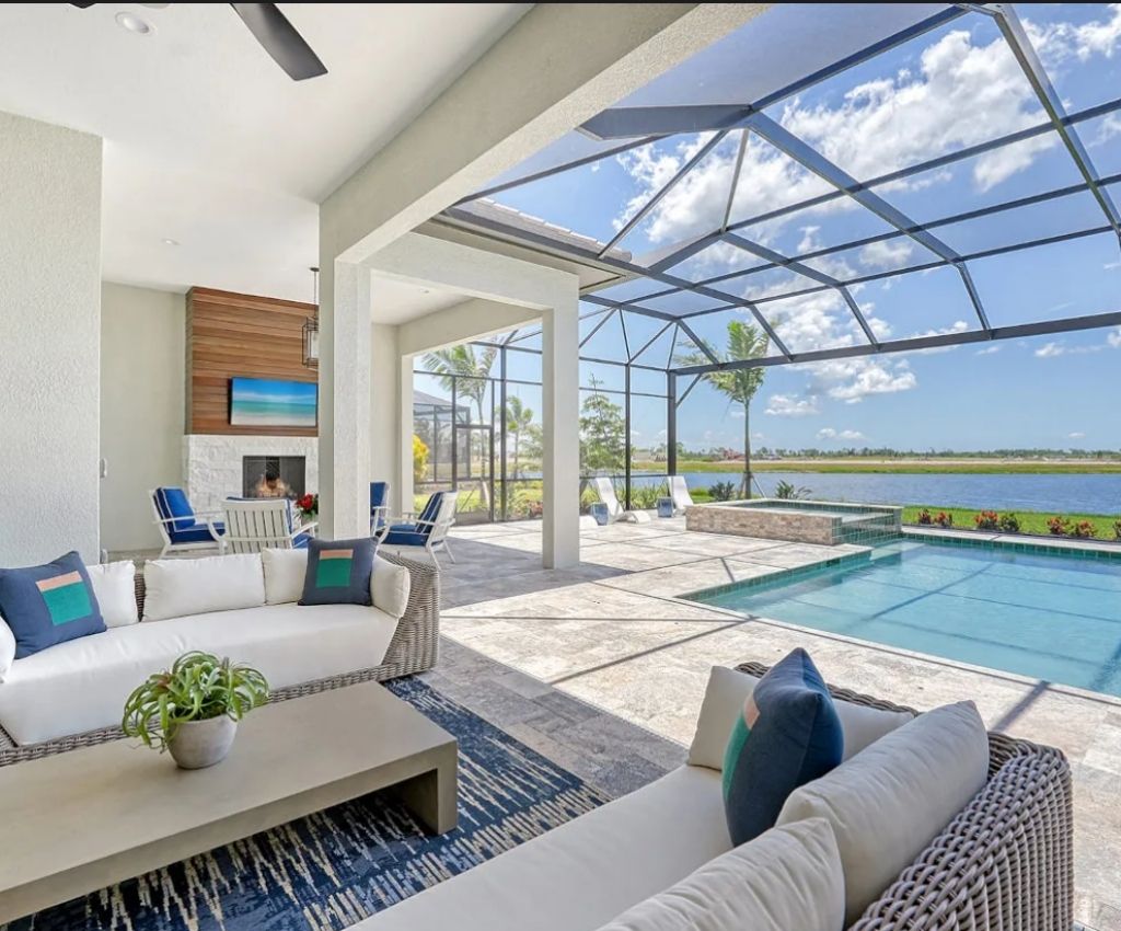 outdoor lanai area with white seating and blue cushions matches the crystal clear pool with glass roof reflecting the clear blue sky